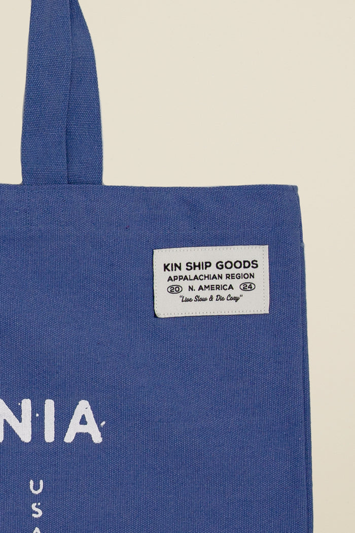 Blue Kin Ship Goods canvas tote with white bear graphic and ‘West Virginia Almost Heaven’ text, laid flat on light background.