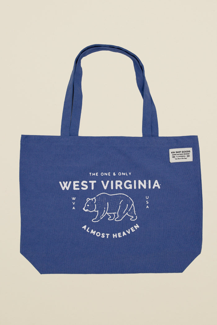 Blue Kin Ship Goods canvas tote with white bear graphic and ‘West Virginia Almost Heaven’ text, laid flat on light background.