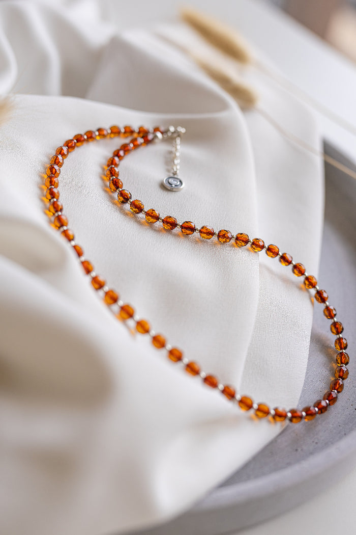 Beaded amber necklace on a white fabric background