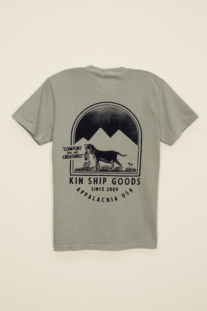 Kin Ship Goods beagle pocket tee in sage with mountain scene and ‘Comfort for all Creatures’ graphic on back.