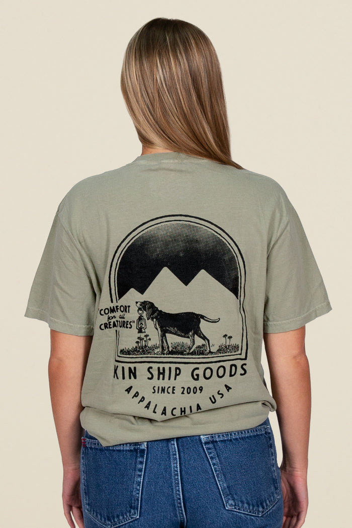 Kin Ship Goods beagle pocket tee in sage with mountain scene and ‘Comfort for all Creatures’ graphic on back.