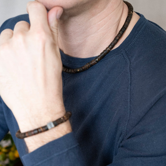 Person wearing a dark blue shirt with a beaded bracelet on their wrist.