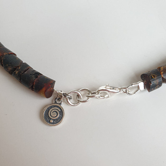 Bracelet with wooden beads and a silver spiral charm on a light gray background