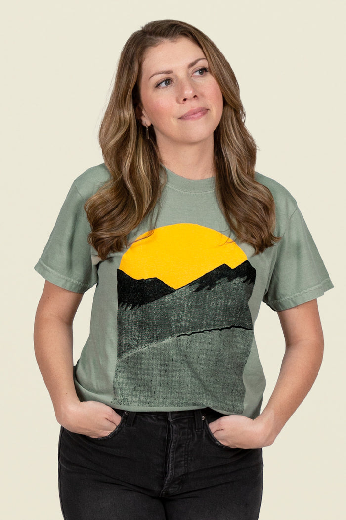 Kin Ship Goods sage green tee with minimalist sunrise over mountains graphic in black and gold, inspired by Appalachian mornings.