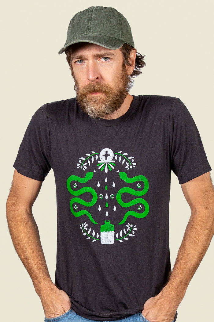 Kin Ship Goods black tee with modern hex sign design featuring green snakes, leaves, and potion bottle—symbolizing protection, strength, and healing.