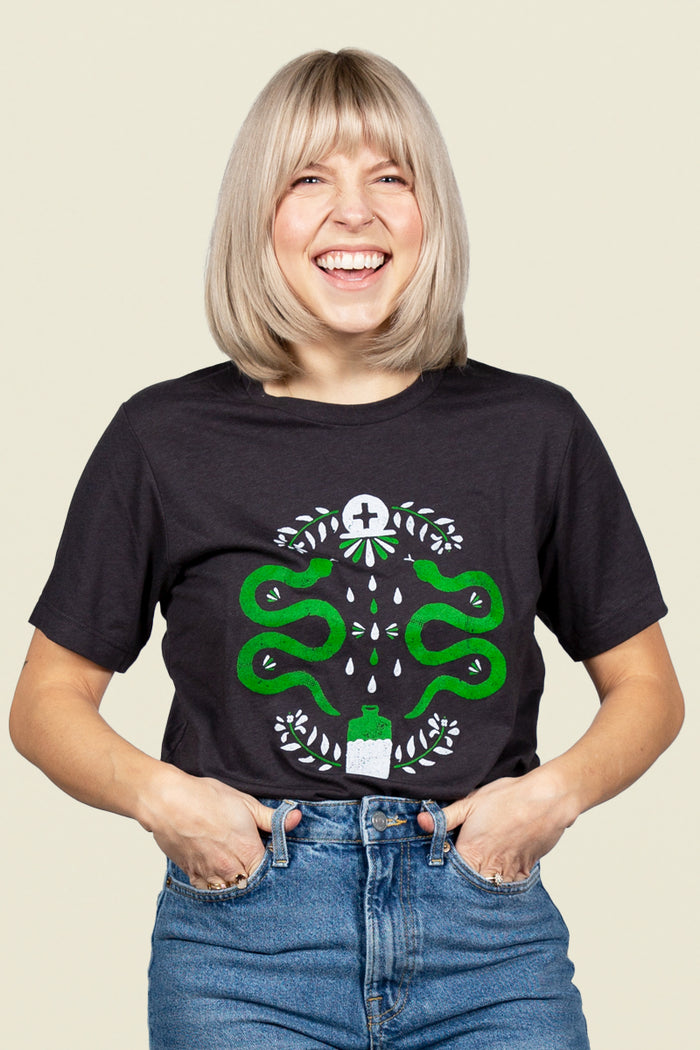 Kin Ship Goods black tee with modern hex sign design featuring green snakes, leaves, and potion bottle—symbolizing protection, strength, and healing.