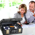 Two people looking into a black Honeywell safe box on a table.