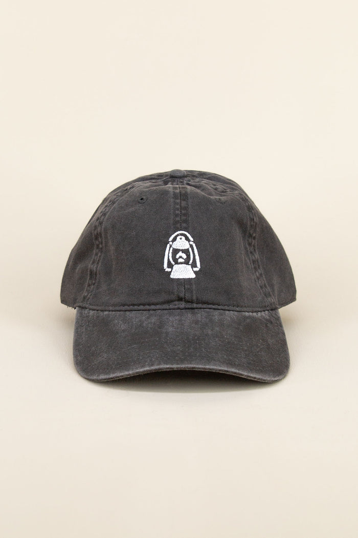 Black Kin Ship Goods baseball cap with white lantern embroidery on front, laid at an angle on neutral background.