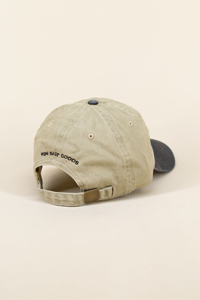 Khaki and black Kin Ship Goods baseball cap with black embroidered lantern graphic, angled on neutral background.