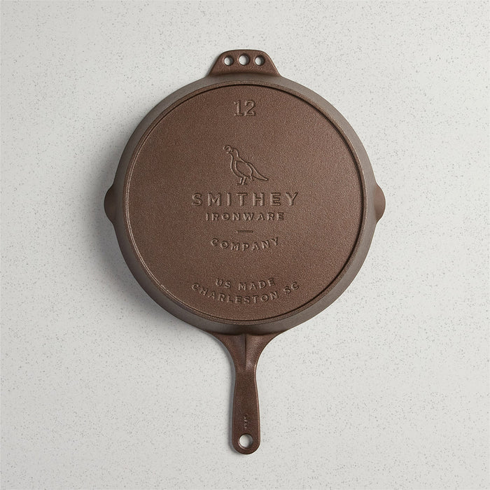 Smithey Ironware No. 12 cast iron skillet with a seasoned black surface, large cooking surface, and sturdy handle.
