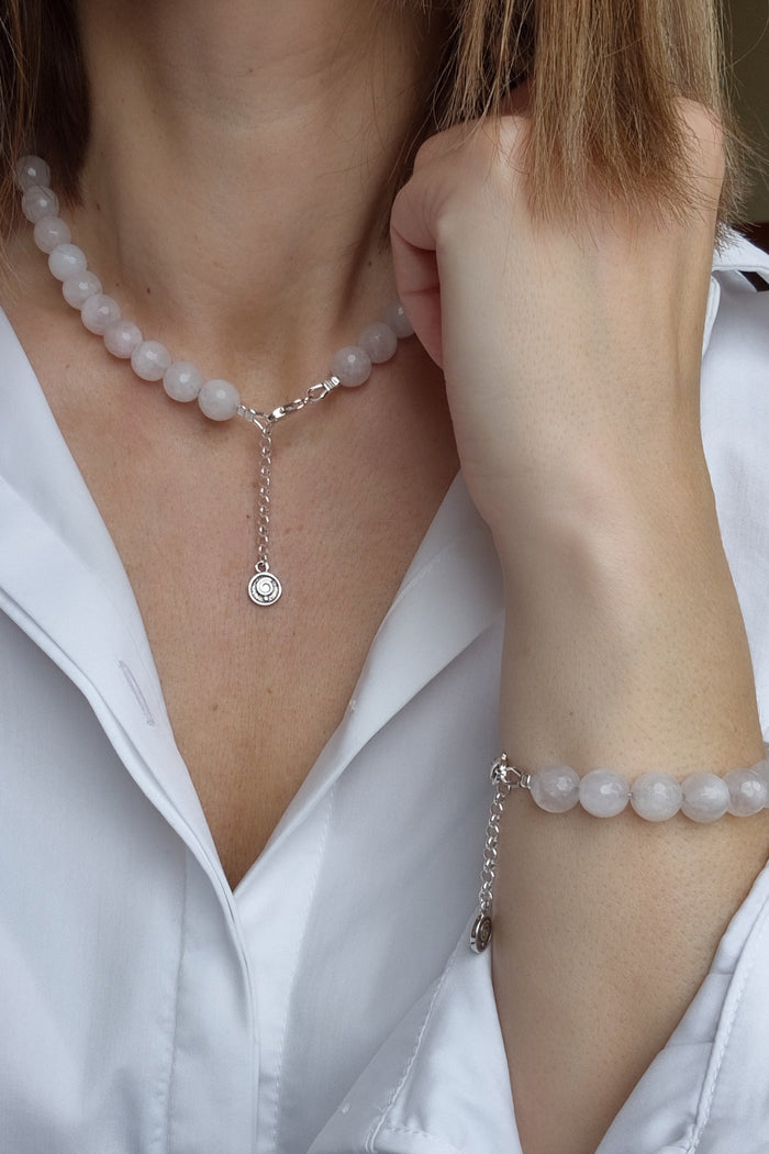 Person wearing a pearl necklace and bracelet with a white shirt.