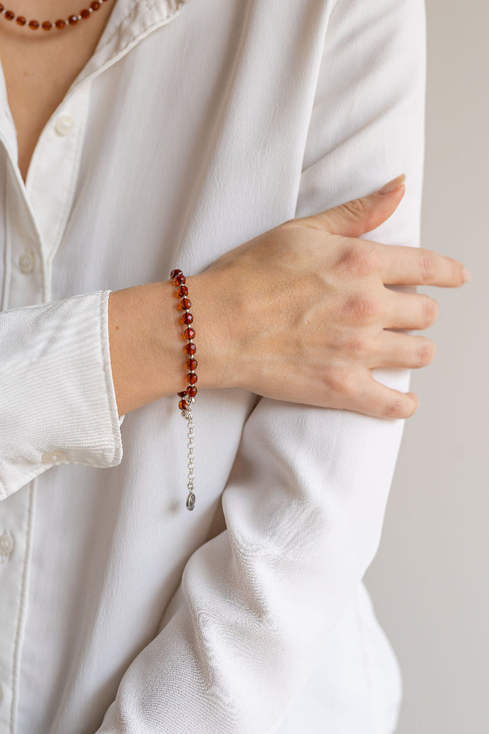 Person wearing a white shirt with a Baltica amber beaded bracelet on a neutral background