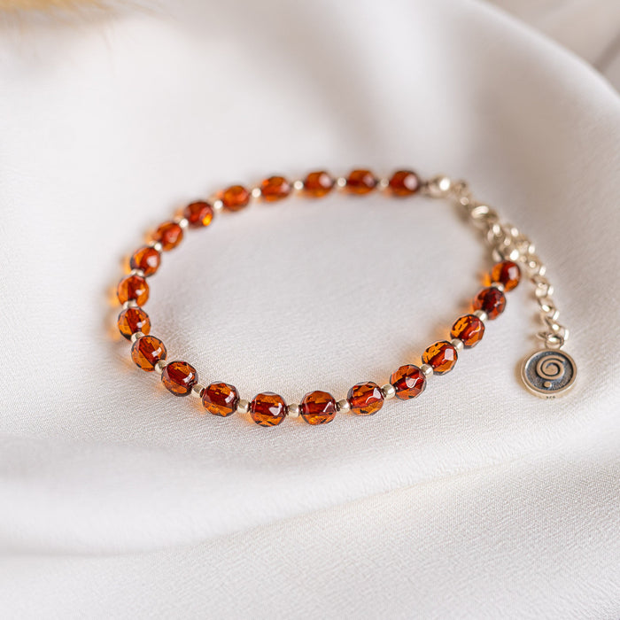 Bracelet with Baltic amber beads on a white fabric background