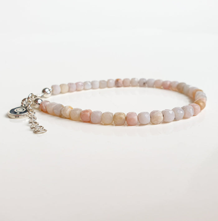 Beaded bracelet with a silver charm on a light background