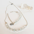 A set of light blue topaz silver jewelry including a necklace and a bracelet with silver accents, displayed on a white surface.