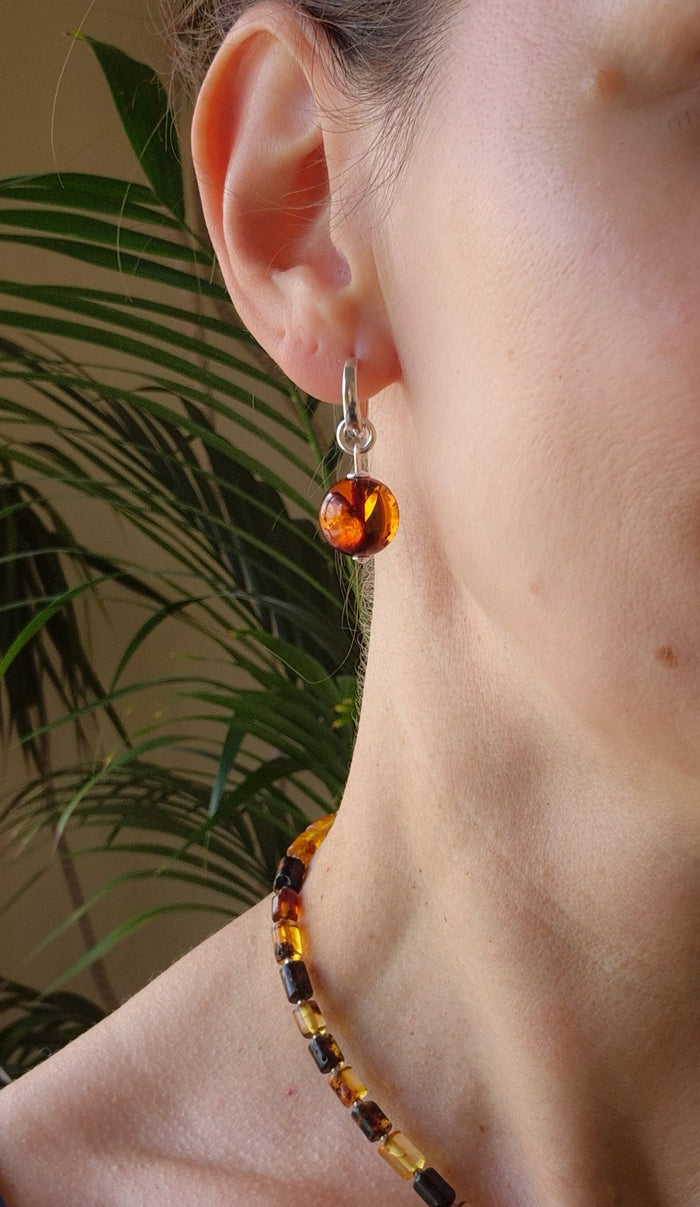 Close-up of a person wearing an amber-colored earring with a blurred background