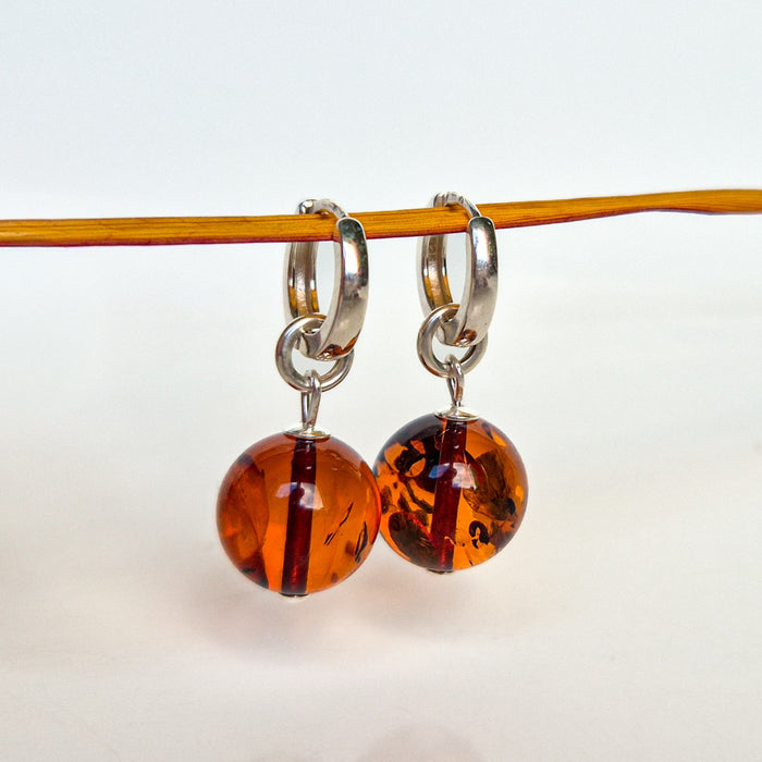 Pair of amber-colored hoop earrings on a thin rod against a white background