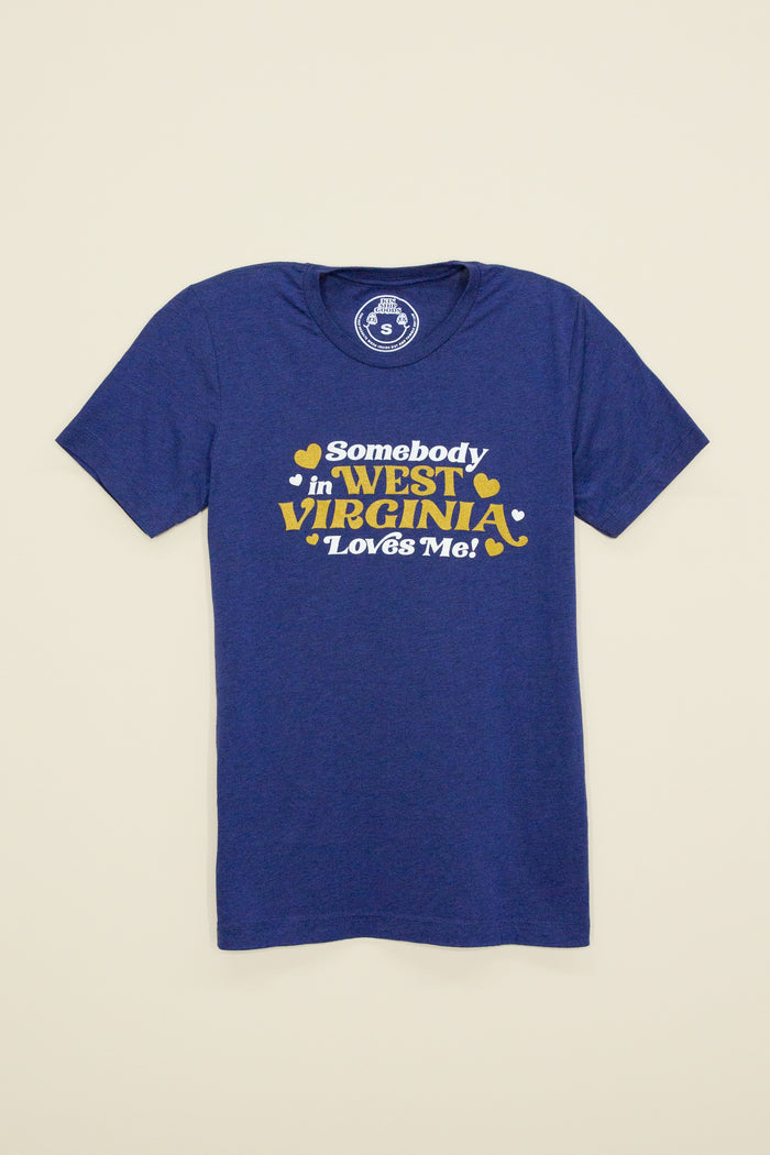 Kin Ship Goods adult tee in heather blue with gold and white ‘Somebody in West Virginia Loves Me!’ retro-style graphic.