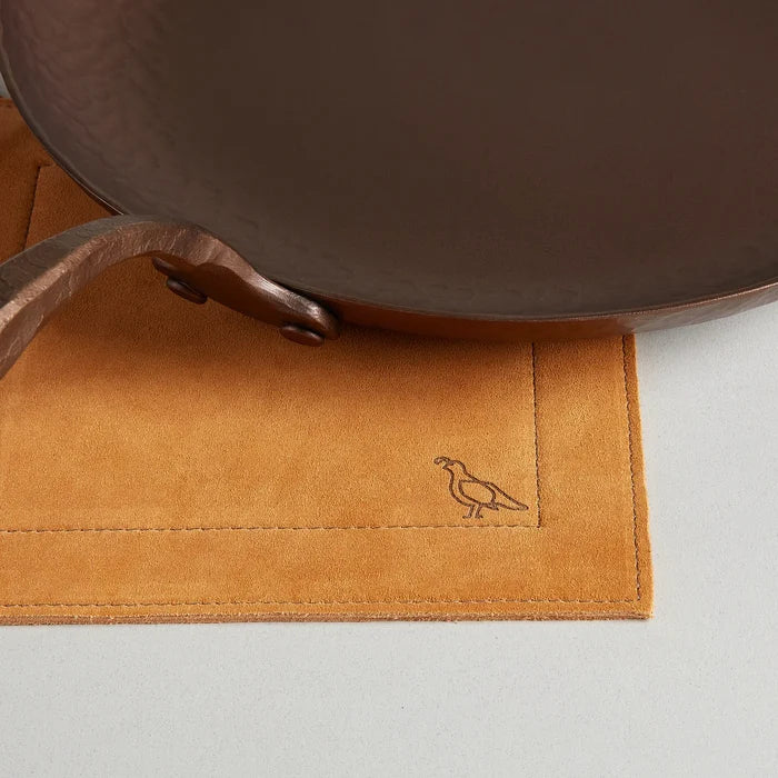 Smithey Ironware suede potholder with textured beige suede surface and loop for hanging, designed for kitchen heat protection.