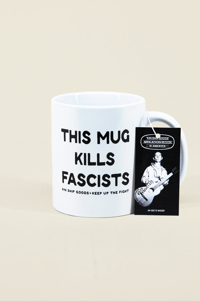 Kin Ship Goods white ceramic mug with 'This Mug Kills Fascists' text, inspired by Woody Guthrie's famous protest guitar.
