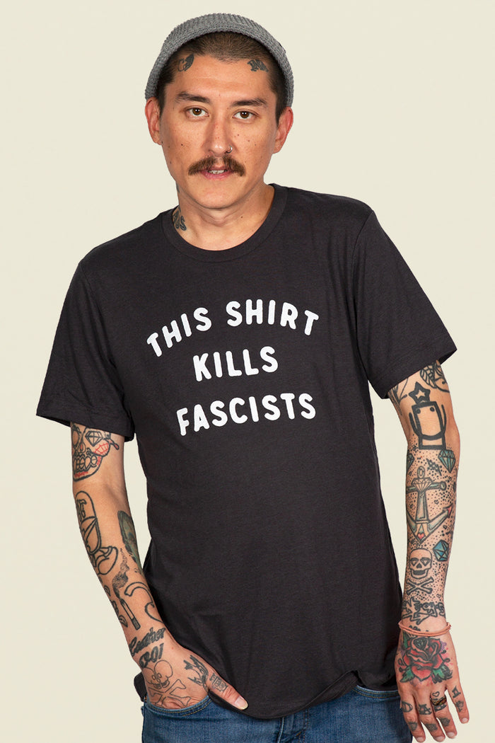 Kin Ship Goods black tee with white text reading 'This Shirt Kills Fascists,' inspired by Woody Guthrie.