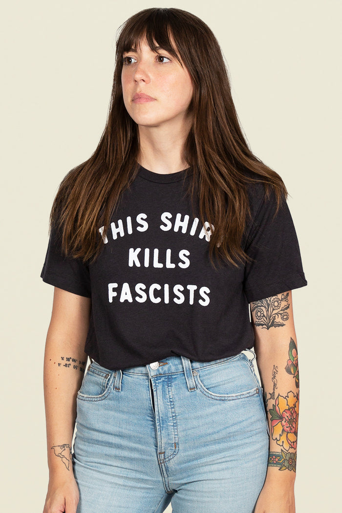 Kin Ship Goods black tee with white text reading 'This Shirt Kills Fascists,' inspired by Woody Guthrie.
