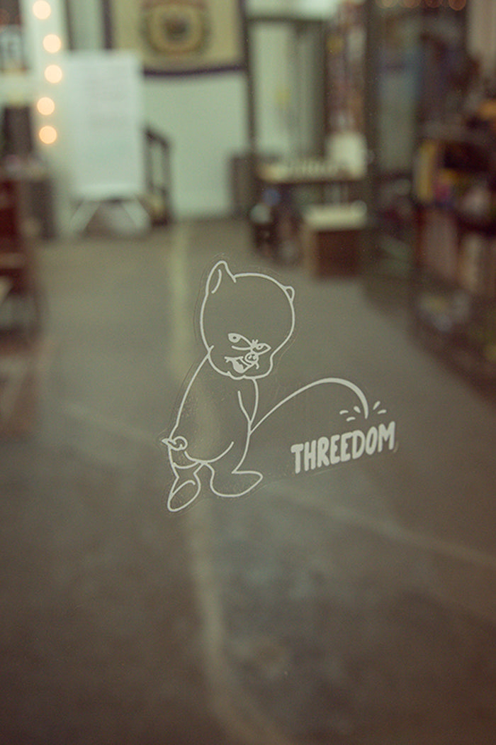 Threedom podcast decal from Kin Ship Goods – parody design featuring a pig peeing on the logo, inspired by classic car decals. Perfect for fans of the show.